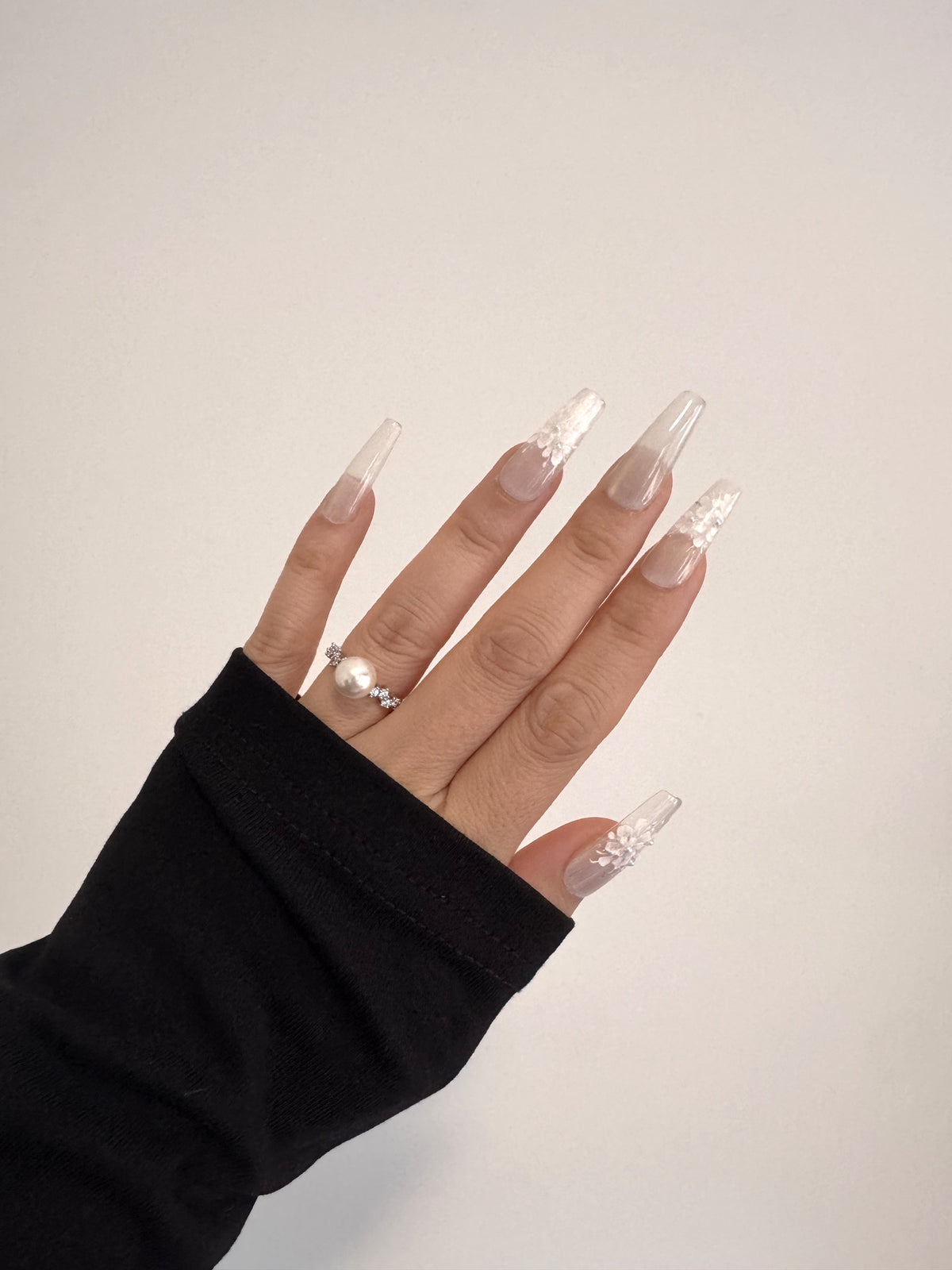 Pearl Bloom hand-painted white floral Long Coffin press-on nails worn on hand with black long sleeve
