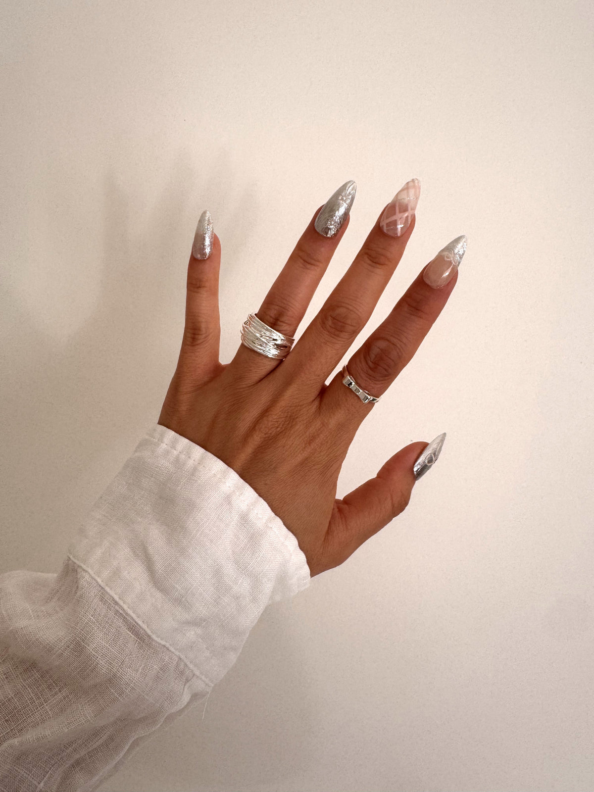 Chrome Ribbon Medium Almond press-on nails worn on hand with silver chrome and pink plaid details